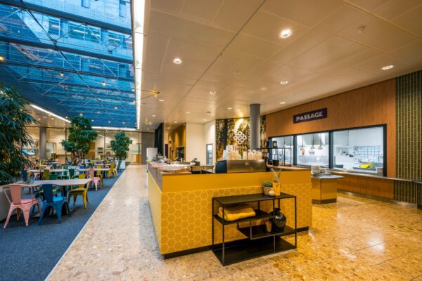Moderne bedrijfskantine aan de Burgemeester Rijnderslaan met kleurrijke zitplaatsen en een open keuken.